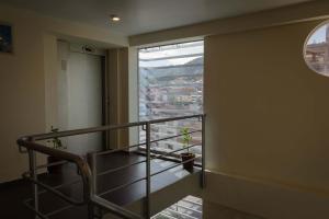 a room with a staircase with a window and plants at Group House Apart Hotel in Cusco