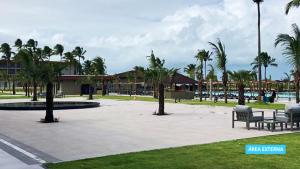 un parc avec des bancs et des palmiers et un bâtiment dans l'établissement Vila Galé Resort Alagoas - All Inclusive, à Barra de Santo Antônio