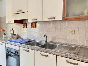 La cuisine est équipée d'un évier en acier inoxydable et de placards blancs. dans l'établissement Casa vacanze CoMì, à Santa Maria del Cedro