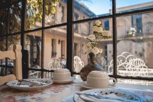 科洛尼亞－德爾薩克拉門托的住宿－Posada de la Flor，窗户上带花瓶的桌子