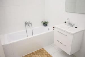 Baño blanco con bañera y lavamanos en Vácz Up! Apartment & Studio en Vác