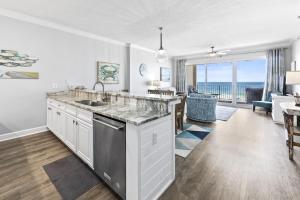 a kitchen with a sink and a living room at Regency Isle Unit 307 in Orange Beach