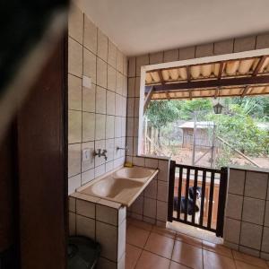 a bathroom with a sink and a dog looking out the window at Granja das Rosas in Juiz de Fora