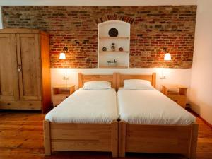 two beds in a bedroom with a brick wall at Heltau Apartments in Cisnădie