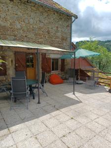 um pátio com uma mesa, cadeiras e um guarda-sol em Gite un bout du sud em Châtel-Montagne