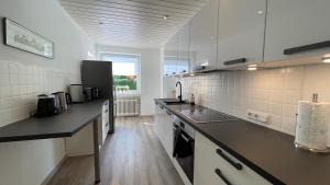 eine Küche mit weißen Schränken und einer Arbeitsplatte in der Unterkunft Fischers Nordseehaus Bungalow mit Garten in Wilhelmshaven