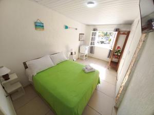 a small bedroom with a green bed and a window at Casa Colomba in Búzios