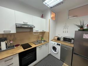 cocina con armarios blancos, lavadora y secadora en Buono apartment, en Zadar