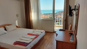 a bedroom with a bed with a desk and a window at Guest House Rona - Free Parking and Sea View in Sveti Vlas