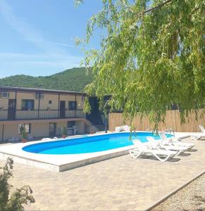 a swimming pool with white chairs next to a building at Casa de vacanta Elisa in Dubova