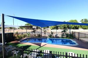 una piscina con dosel azul sobre una valla en Leichhardt Accommodation en Mount Isa