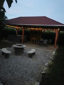 a patio with two benches and a pavilion with lights at Zso-Zé Apartman in Tiszafüred
