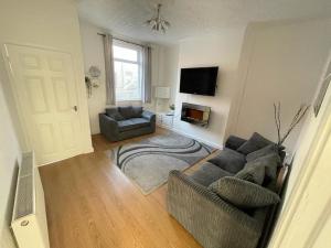 a living room with two couches and a flat screen tv at Cheerful 2 bedroom house in Hindley