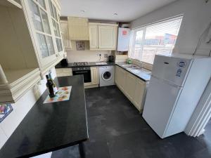 a kitchen with a white refrigerator and a sink at Cheerful 2 bedroom house in Hindley