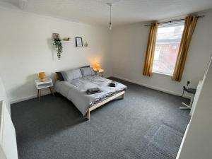 Schlafzimmer mit einem Bett, einem Tisch und einem Fenster in der Unterkunft Cheerful 2 bedroom house in Hindley