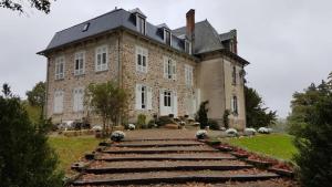 een groot stenen gebouw met een trap ervoor bij Gîtes du Castellare in Le Chalard