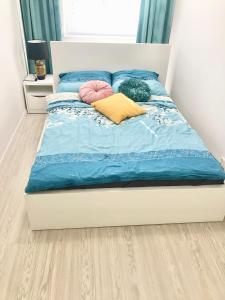 a bed with blue and yellow pillows on it at Orłowska by the Sea Apartment in Gdańsk