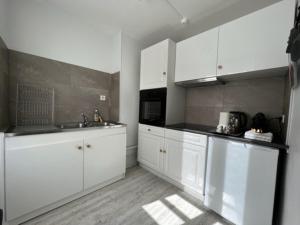 a kitchen with white cabinets and a sink and a microwave at Appartement hypercentre Fontainebleau in Fontainebleau