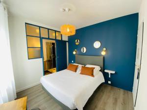 Un dormitorio con una pared azul y una cama blanca en Hotel Saint-Michel, en Dinard