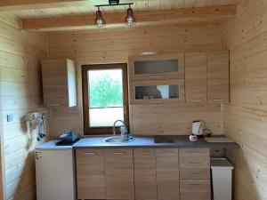 a kitchen with wooden walls and a sink and a window at Domek u Kamińskich in Przyborów