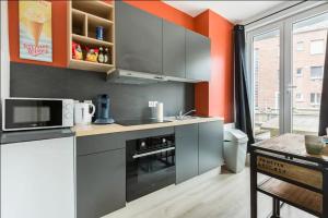 a kitchen with gray cabinets and an orange wall at Esprit africain, Appartement, Balcon, Centre in Valenciennes