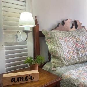 um quarto com uma cama e uma mesa com um candeeiro em Casa do Pinheiro Petrópolis em Petrópolis