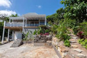 a house on a hill with flowers and plants at Villa Les Belles Vues de St Jean in Saint Barthelemy