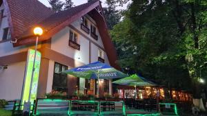 a restaurant with tables and umbrellas in front of a building at Pensiunea Happy Inn in Vatra Dornei +55 photos