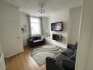 ein Wohnzimmer mit einem Sofa und einem TV in der Unterkunft Cheerful 2 bedroom house in Hindley