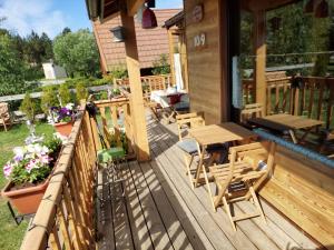 une terrasse en bois avec des tables et des chaises sur une maison dans l'établissement Confortable Chalet pie des pistes Pyrénées 2000, à Bolquère-Pyrénées 2000 42 autres photos