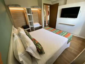 1 dormitorio con 1 cama con almohadas y TV en Hot Beach Suites en Olímpia