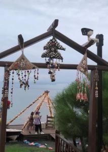 a group of people standing under a structure with beads at Marbella Kale Beach in Akçakale