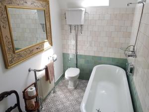 a bathroom with a tub and a toilet and a mirror at Cambus O' May Traditional Highland Hotel in Ballater