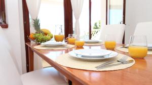 una mesa de madera con platos y vasos de zumo de naranja en Villa Flamingo, en Makarska
