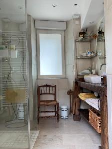 a bathroom with a glass shower and a chair at La Berlue Bayeux in Saint-Vigor-le-Grand