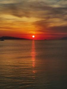 a sunset over the water with the sun setting at Ithaca in Perdika