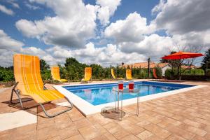 a pool with two chairs and a table and an umbrella at Casa Lilly in Labin