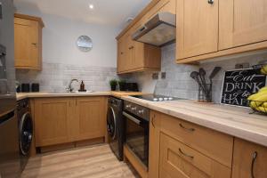 a kitchen with wooden cabinets and a sink and a dishwasher at Lovely Apartment close to the Town Centre & Train Station in Northampton