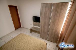 a room with a television and a large wooden cabinet at Riviera Park in Caldas Novas