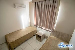a small room with two beds and a window at Riviera Park in Caldas Novas
