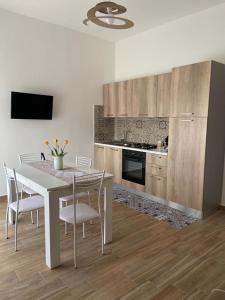 y cocina con mesa blanca, sillas y fogones. en Appartamenti Al Fardella 365 en Trapani