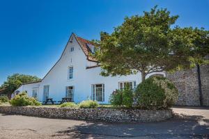 布莱克尼The Manor Coastal Hotel & Inn, Blakeney - The Coaching Inn Group的一栋白色的房子，前面有一棵树