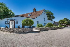 a white house with a stone wall in front of it at The Manor Coastal Hotel & Inn, Blakeney, Norfolk in Blakeney