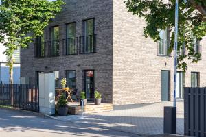 ein Backsteinhaus mit schwarzen Fenstern und einem Zaun in der Unterkunft Apartamentai su terasa in Palanga