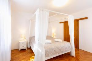 a bedroom with a white canopy bed with white curtains at Casa Lilly in Labin +25 photos