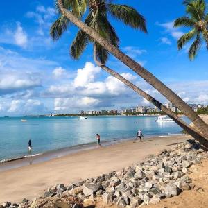 a group of people walking on a beach with palm trees at Seaside Season Maceió in Maceió