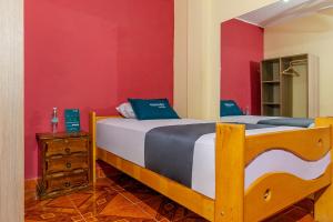 1 dormitorio con cama y pared roja en Ayenda Muñoz, en Ica