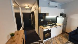 a small kitchen with white cabinets and a refrigerator at Gold Horizon Apartament Solny Resort in Kołobrzeg