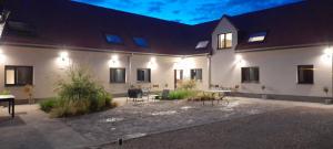 un grand bâtiment blanc avec des tables et des chaises dans une cour dans l'établissement Côté Grange, à Tournai