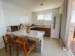 a kitchen with a table and chairs and a refrigerator at Loft Grécia In in Arraial do Cabo +5 photos